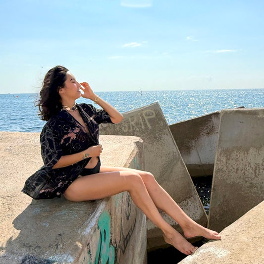 Woman sitting on a concrete ledge by the ocean